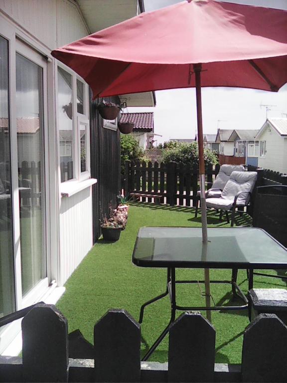 a table with a red umbrella on a patio at yeolde 2 bedroom Seashak Detached Cottage LOW 2026 PRICES NEWLY REFURBISHED PLUS FREE ALL ELECTRIC ENJOY in Bridlington