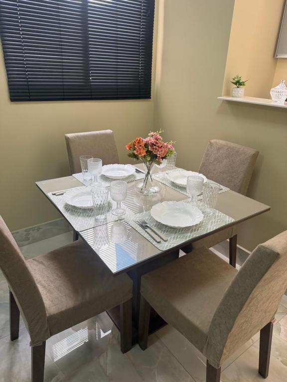 a dining room table with plates and flowers on it at Apartamento Espaço e Conforto Cerejeiras in Várzea Grande