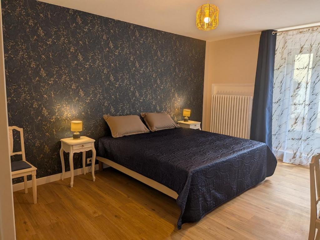 a bedroom with a bed and two tables with lamps at Gîte LM in Bourbonne-les-Bains