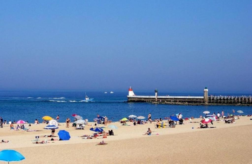 a group of people on a beach with a pier at La croisière in Capbreton