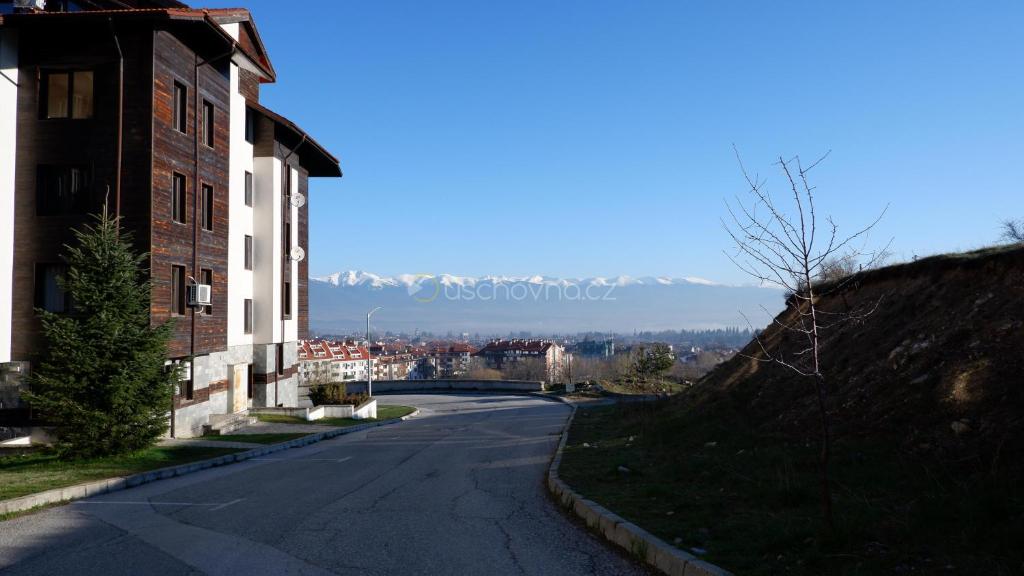an empty street next to a building and a hill at Apartmán Daniela in Bansko
