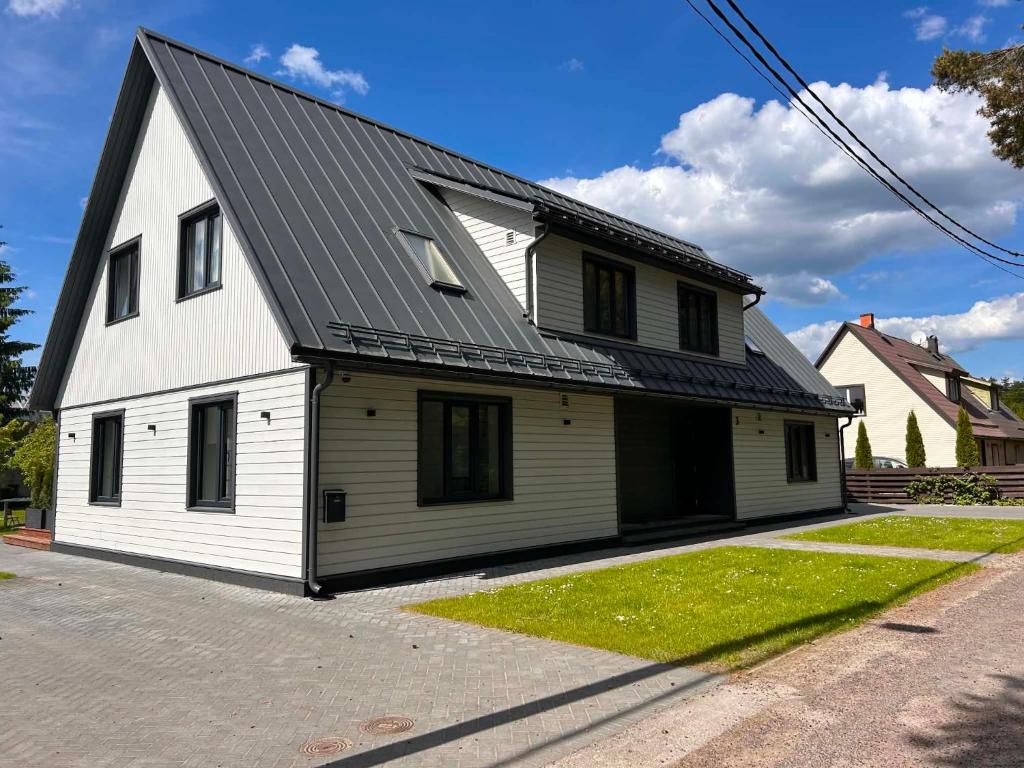 a white house with a black roof at Roosi Kodumajutus in Pärnu