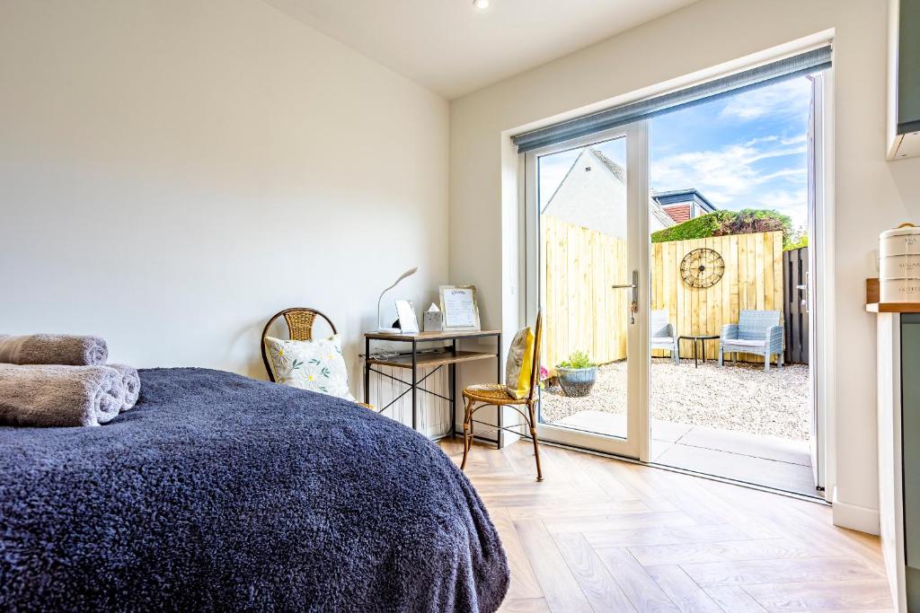 a bedroom with a bed and a sliding glass door at The Hide at St Andrews in Fife