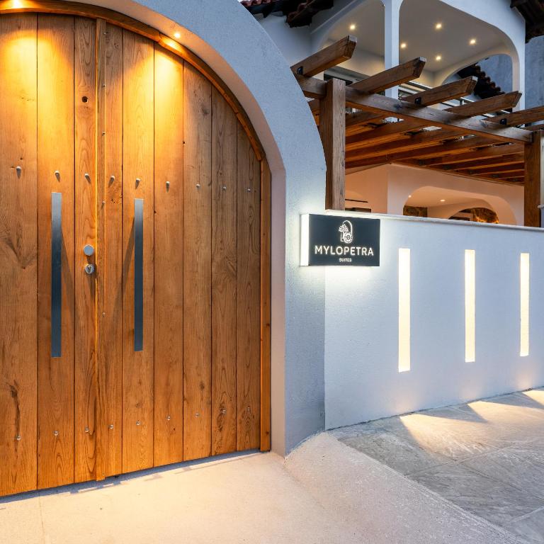a wooden door in a building with a sign on it at Mylopetra Suites Sarti in Sarti