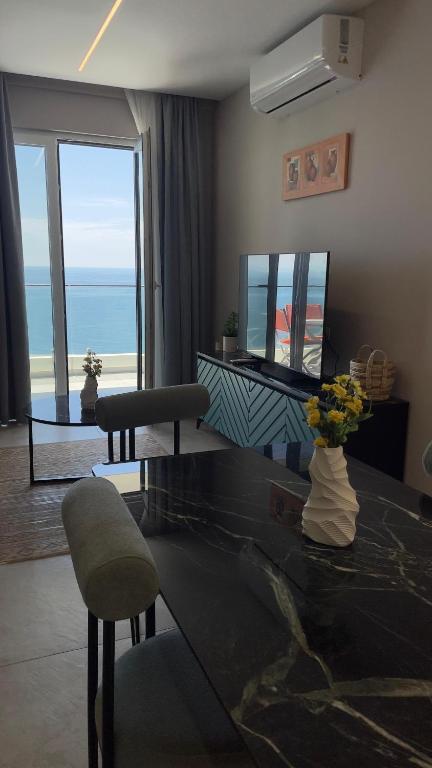 a living room with a table with a view of the ocean at DreamStay Lezha Apartments - Ilyonis Residence in Lezhë