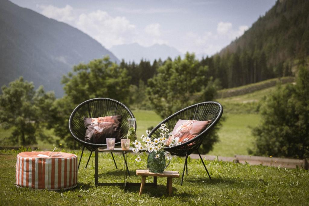 two chairs and a table in a field with mountains at Pfaffingerhof Antholz in Masserie