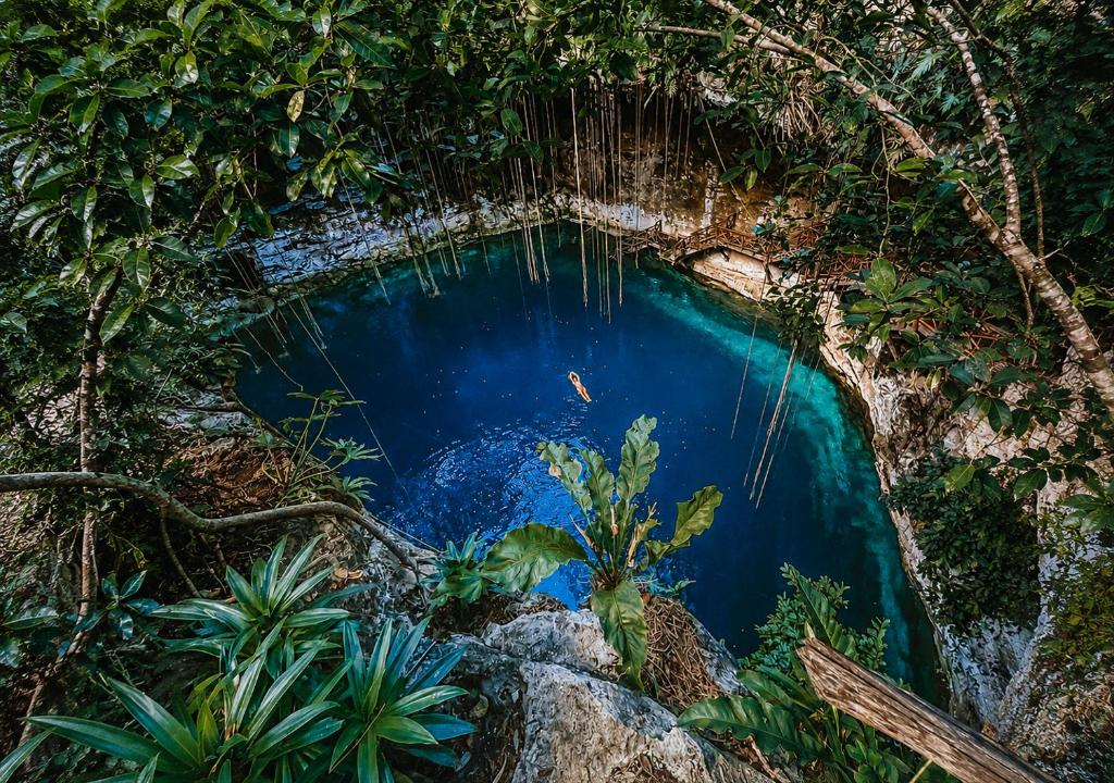 a pool of blue water in the jungle at Hotel Boutique Cenote Secreto Maya in Valladolid