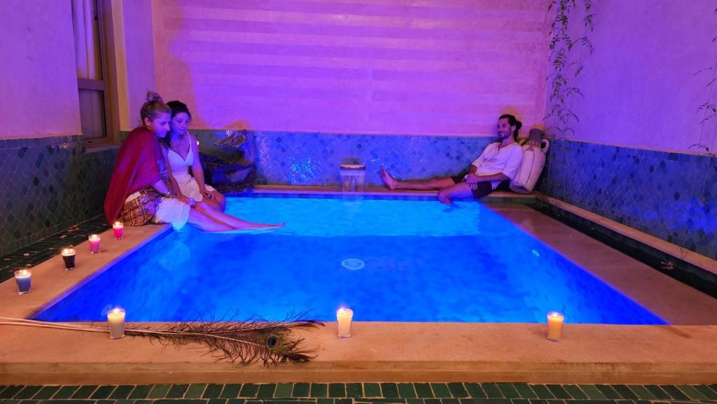 a group of women sitting around a swimming pool with candles at Riad Atrium & Spa in Marrakesh