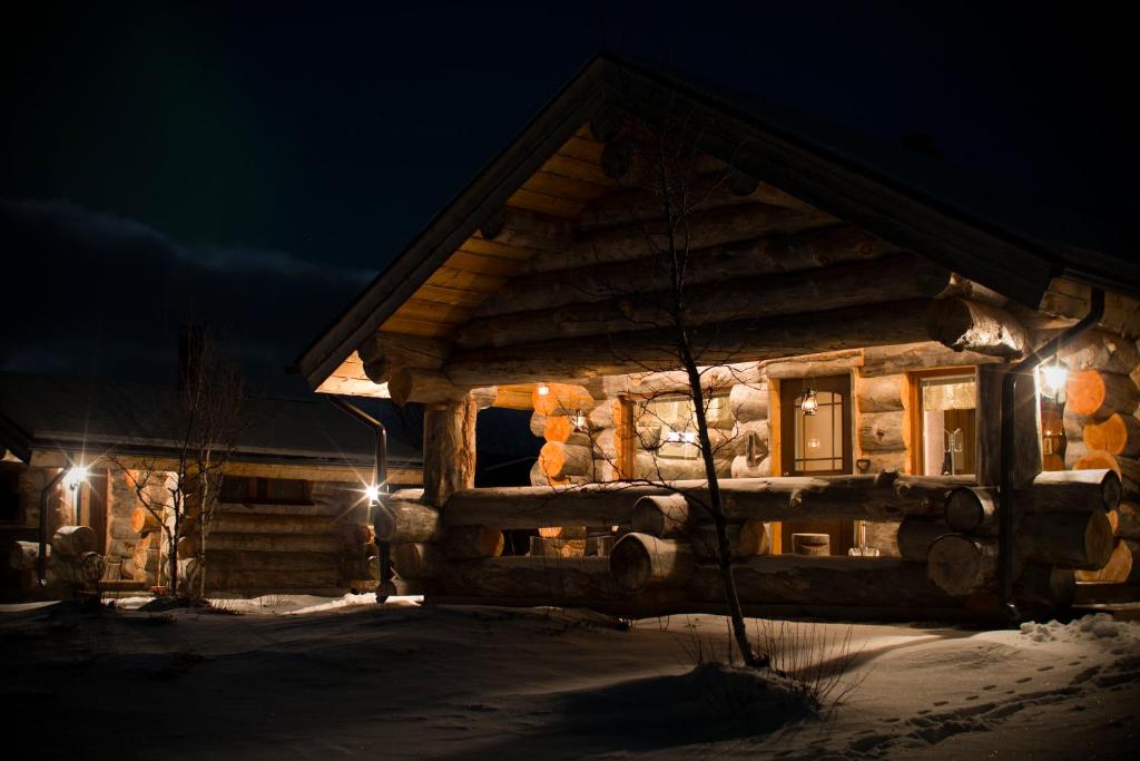 une cabane en rondins dans la neige la nuit dans l'établissement Osman Kelohovi, à Utsjoki