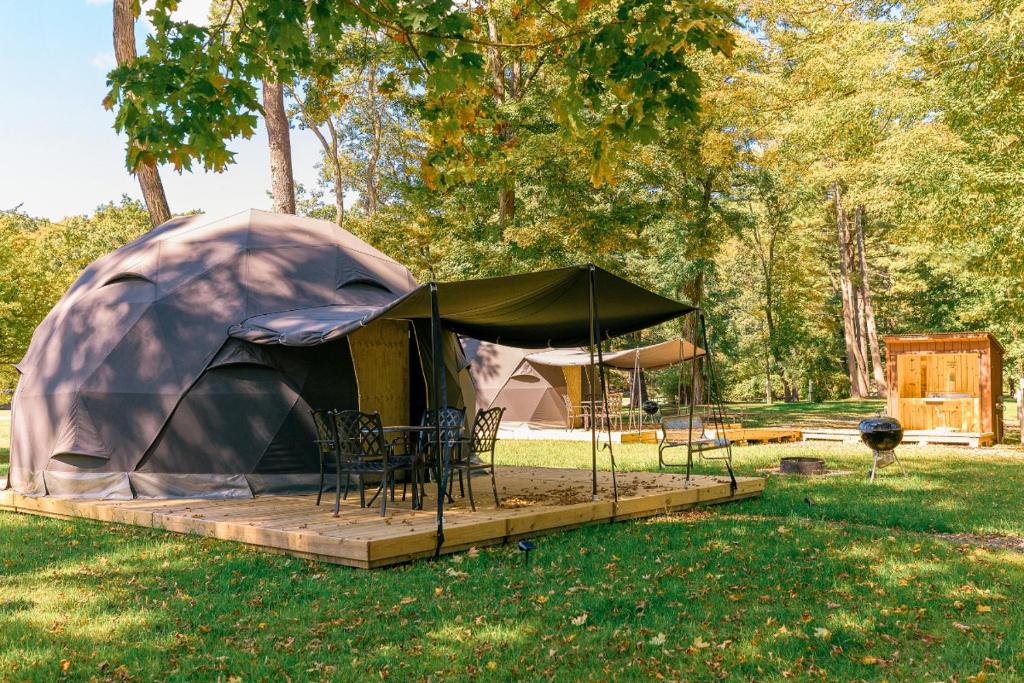 a tent with chairs and tables in a yard at Luxury Catskill Mountains Dome Retreat in Gilboa