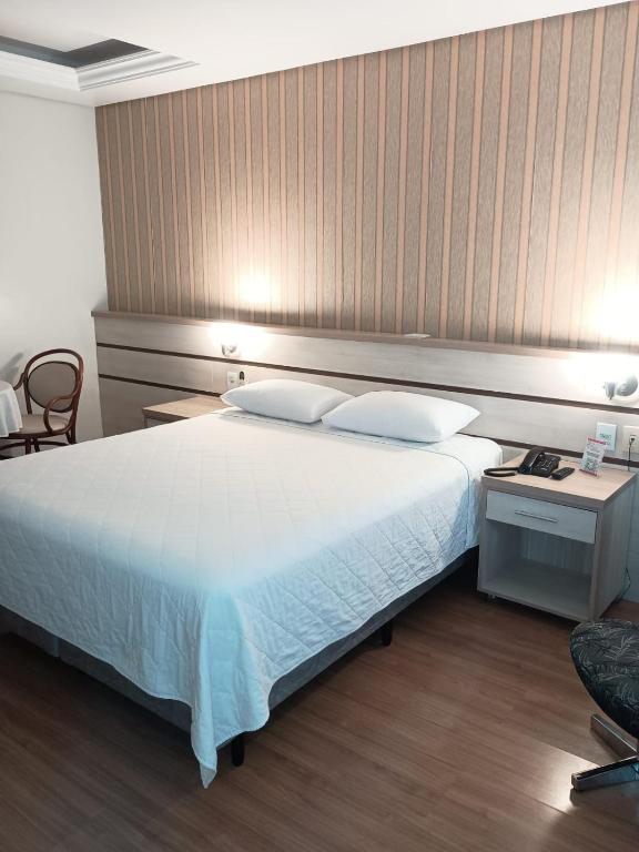 a bedroom with a large white bed and a chair at Hotel Premier in Santa Rita