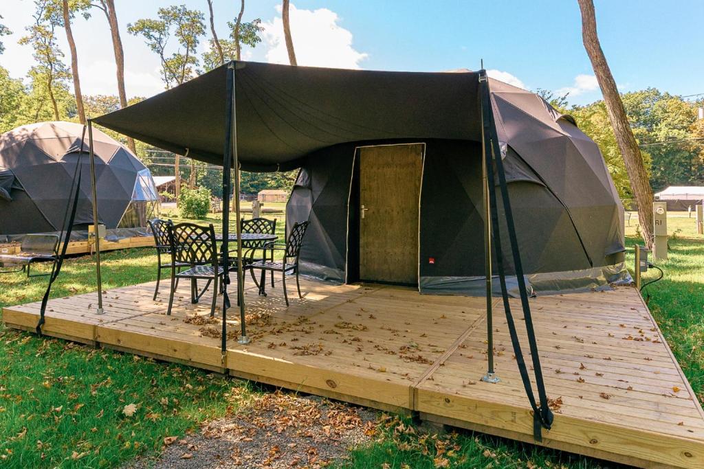 a tent with a table and chairs on a wooden deck at Boutique Glamping Dome in the Catskill Mountains in Gilboa