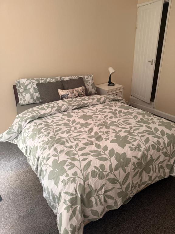 a bedroom with a bed with a green and white comforter at Cosy Heavens in Quinton