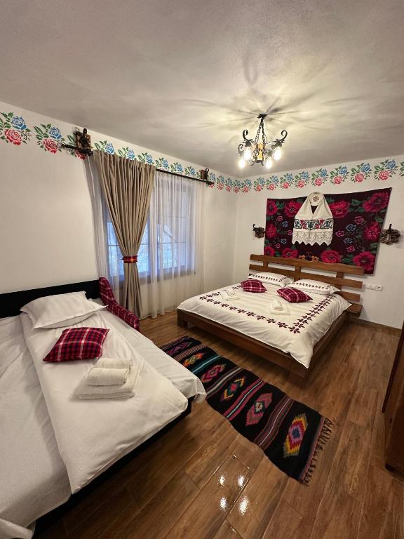 a bedroom with two beds and a chandelier at Pensiunea Floare de Maramures in Vadu Izei