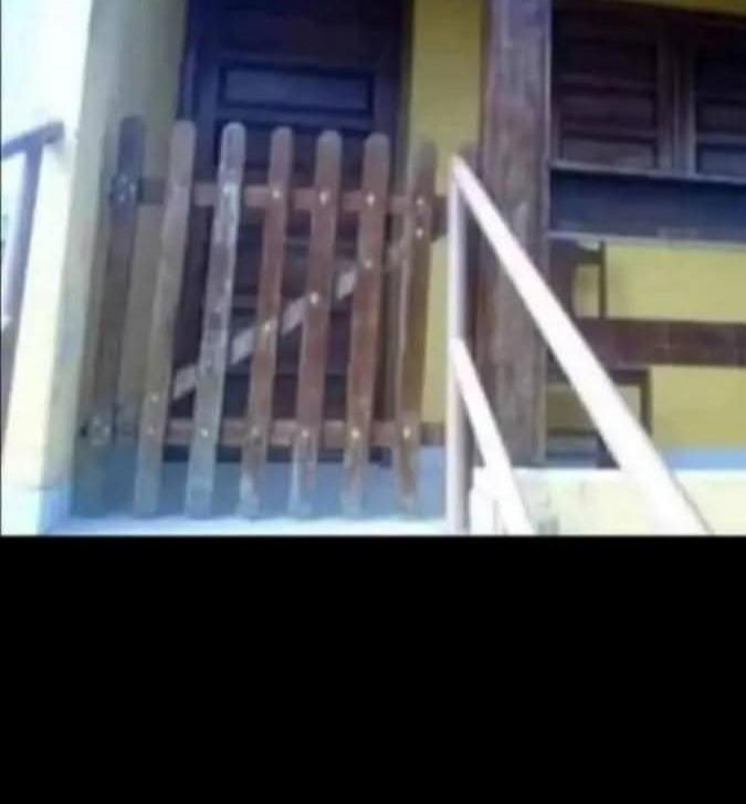 a porch with a wooden railing and a door at Hospedagem da Paty in Ilhéus
