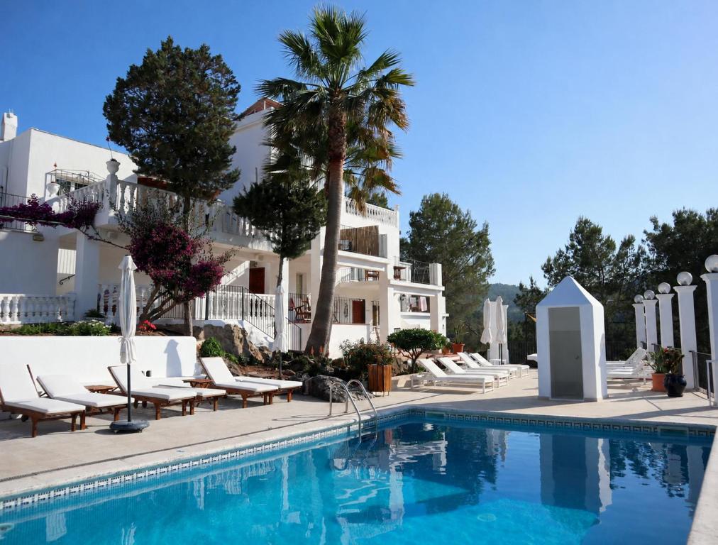 a pool at a hotel with chairs and palm trees at Hotel Rural Can Maries in Puerto de San Miguel