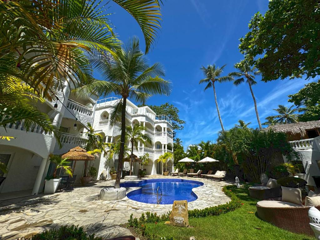 a large white house with a swimming pool and palm trees at Hotel Villa Taina in Cabarete