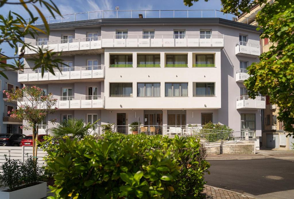 an apartment building with balconies and trees at Hotel Palladio in Caorle
