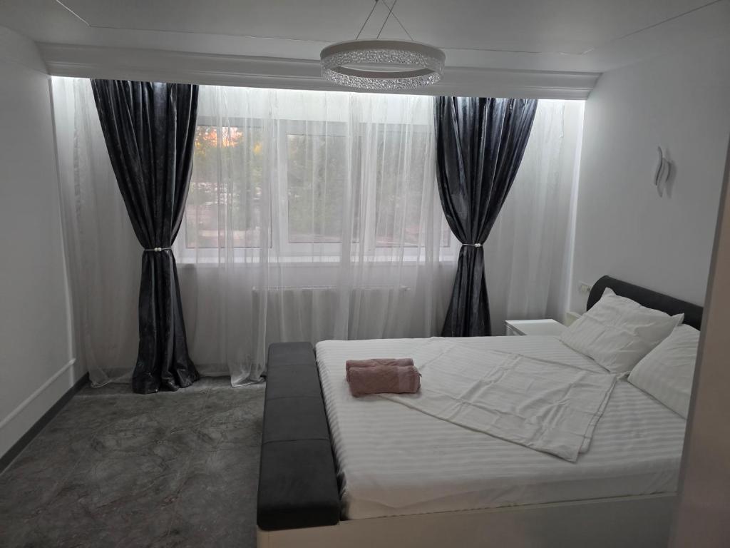 a bedroom with a white bed and a window at Sky luxury apartment in Giurgiu
