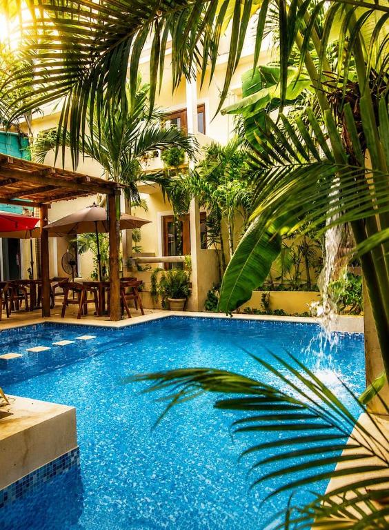 a swimming pool with a palm tree next to a building at Hotel San Vicente in Playa del Carmen