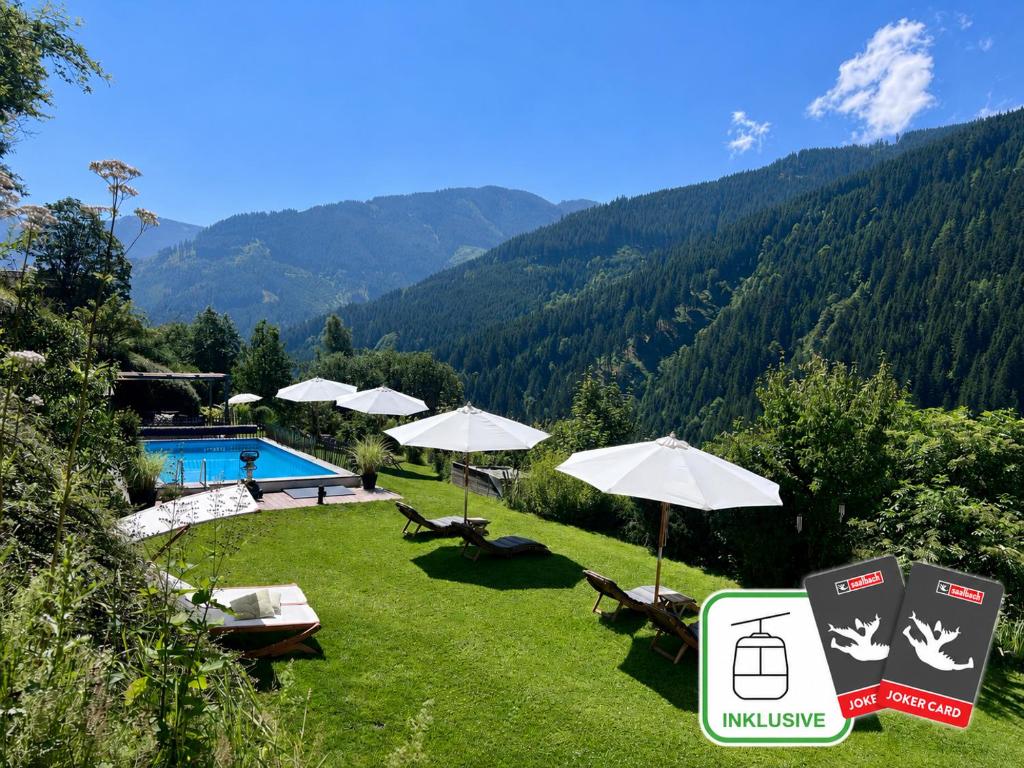 a resort with a swimming pool and chairs and umbrellas at ALM SEASONS Premium Chalet & Studios in Saalbach-Hinterglemm