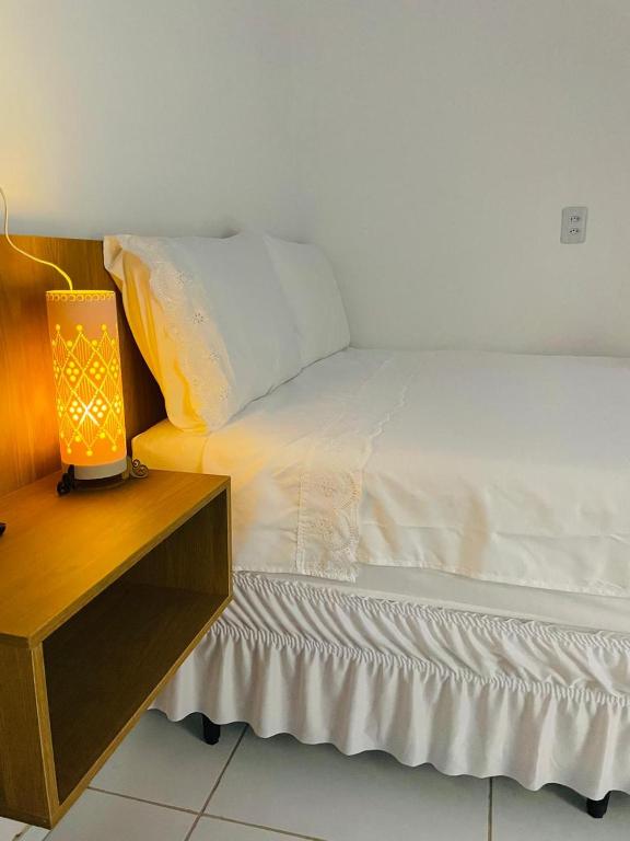 a bed with a lamp next to a night stand at Chalés Areias in Barreirinhas