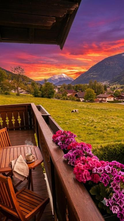 a wooden deck with a table and flowers on it at Boutique73 Sunset in Altossiach