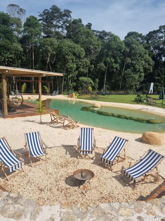 a group of lounge chairs and a swimming pool at Ecovila Coração da Mata in Brumadinho