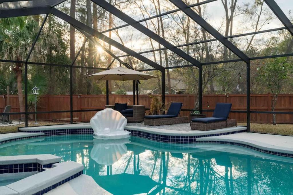 a pool with an umbrella and chairs and a fountain at The Summer House - Private Pool Firepit in Jacksonville
