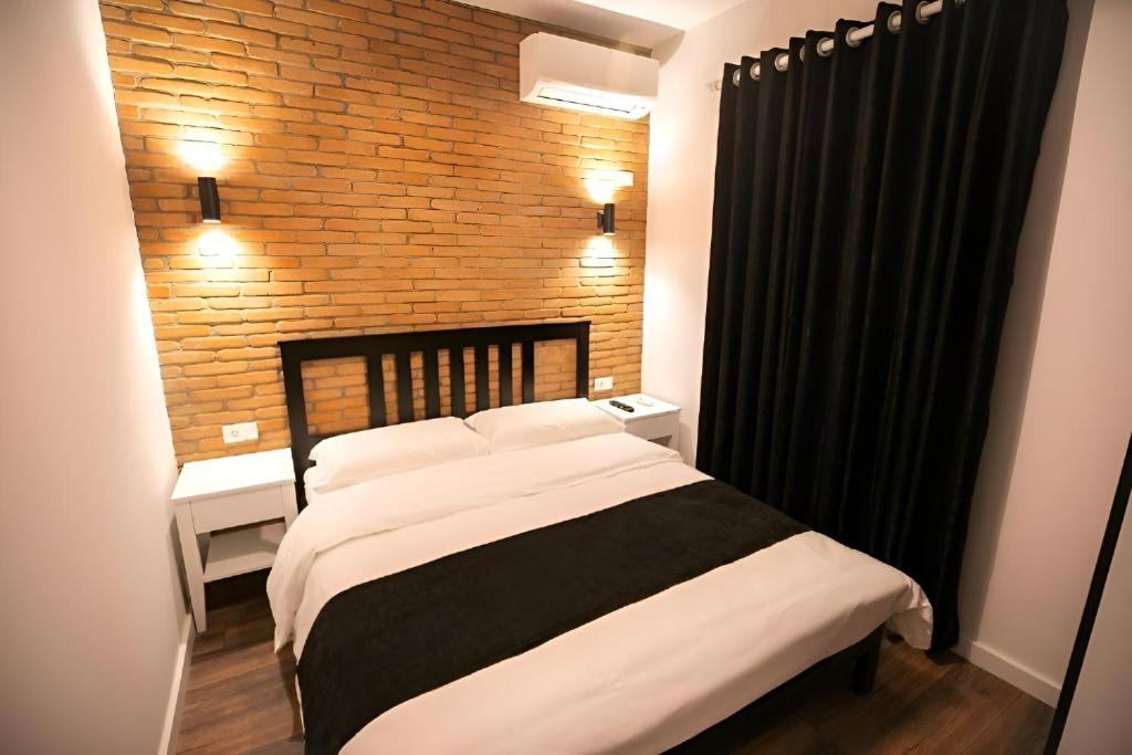 a bedroom with a bed and a brick wall at Hotel Sidi in Tirana