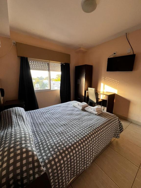 a bedroom with a bed with a checkered blanket and a window at Hotel Andino in La Rioja