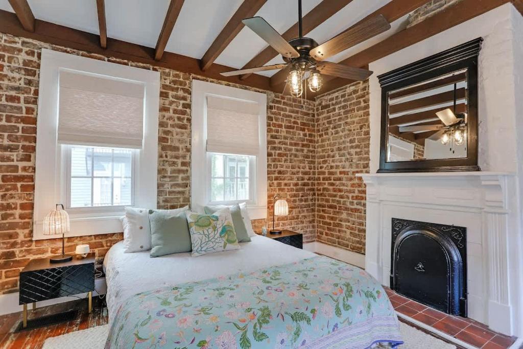 a bedroom with a bed with a fireplace and a ceiling fan at Brick house in Savannah
