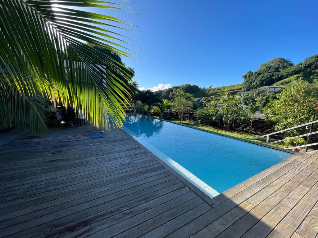 a pool with a wooden deck and a palm tree at Tahiti Green Lodge in Punaauia