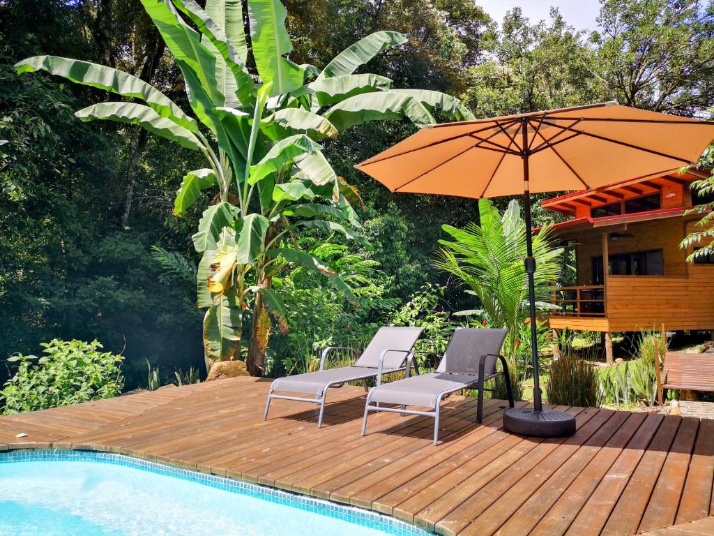 a deck with two chairs and an umbrella next to a pool at Thoas Lodge in Coronado