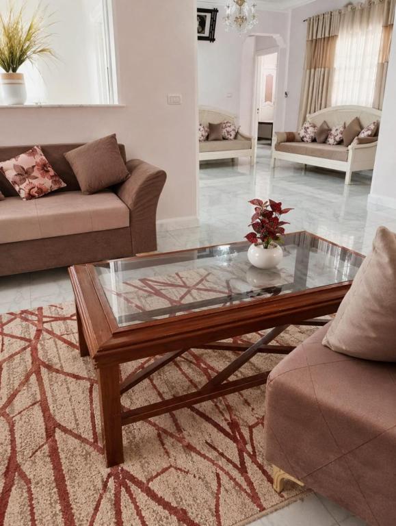 a living room with a glass coffee table and couches at Maison au rez-de-chaussée à Mahdia rejiche in Mahdia