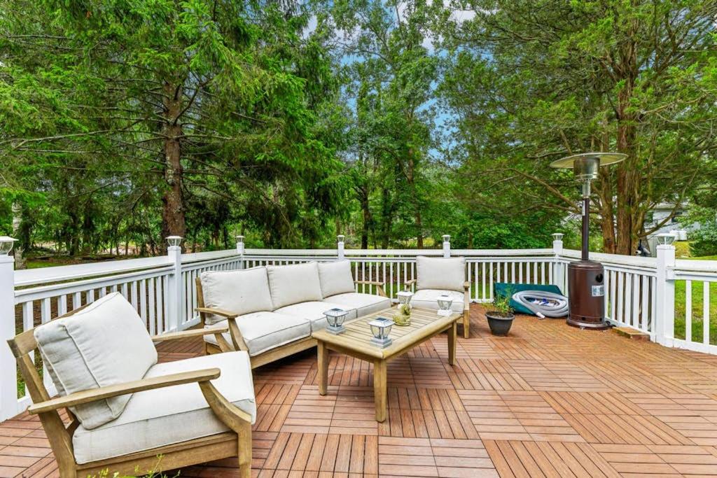 eine Terrasse mit Stühlen und einem Couchtisch auf einem weißen Zaun in der Unterkunft Tree Canopy Oasis in East Quogue