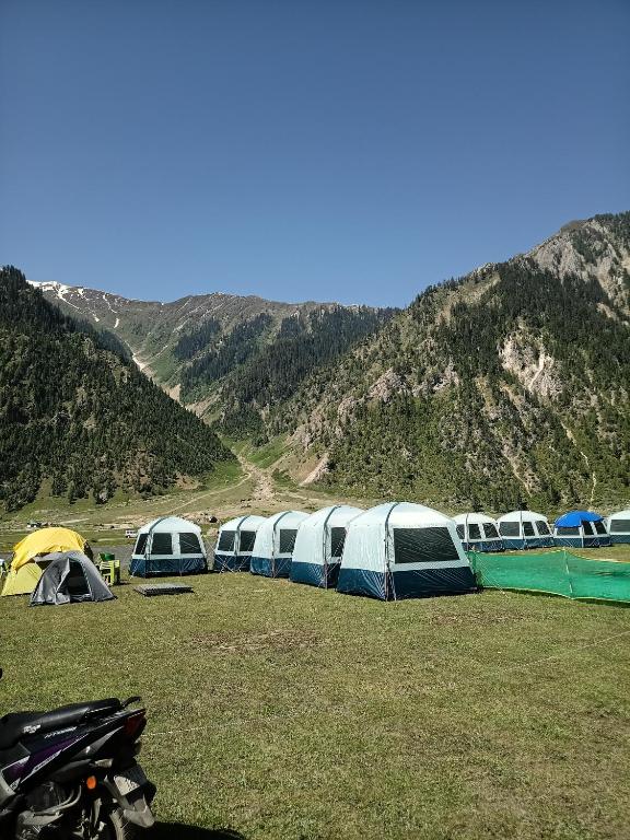 a group of tents in a field with mountains at Nomad's Nest Camp in Wāmpor