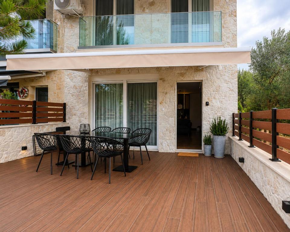 a deck with a table and chairs on a house at Olea Luxury Living in Nea Fokea