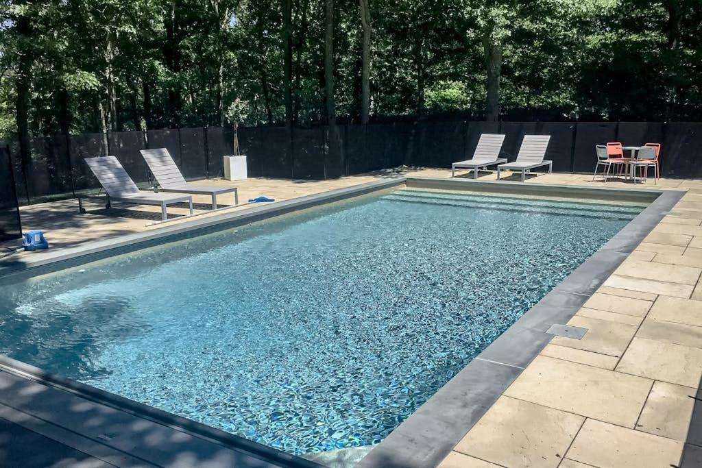 a swimming pool with two chairs and a table at Hamptons Hideaway in Hampton Bays