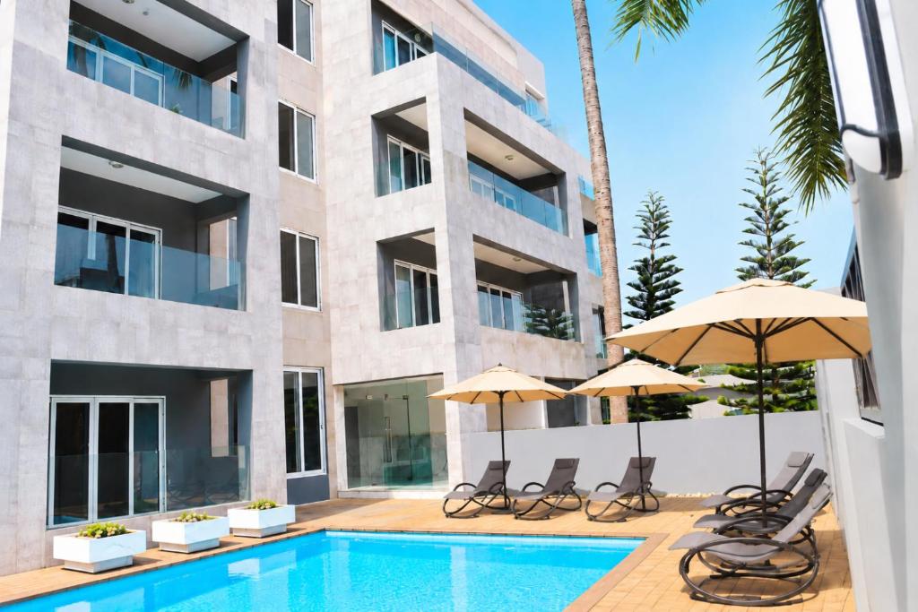 a swimming pool with chairs and umbrellas next to a building at THE POOL LABONE in Accra