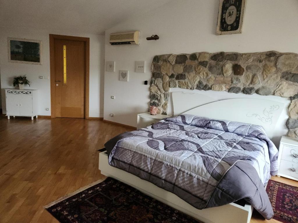 a bedroom with a large bed with a stone wall at Il Pozzo dei desideri Shabby in Spilimbergo