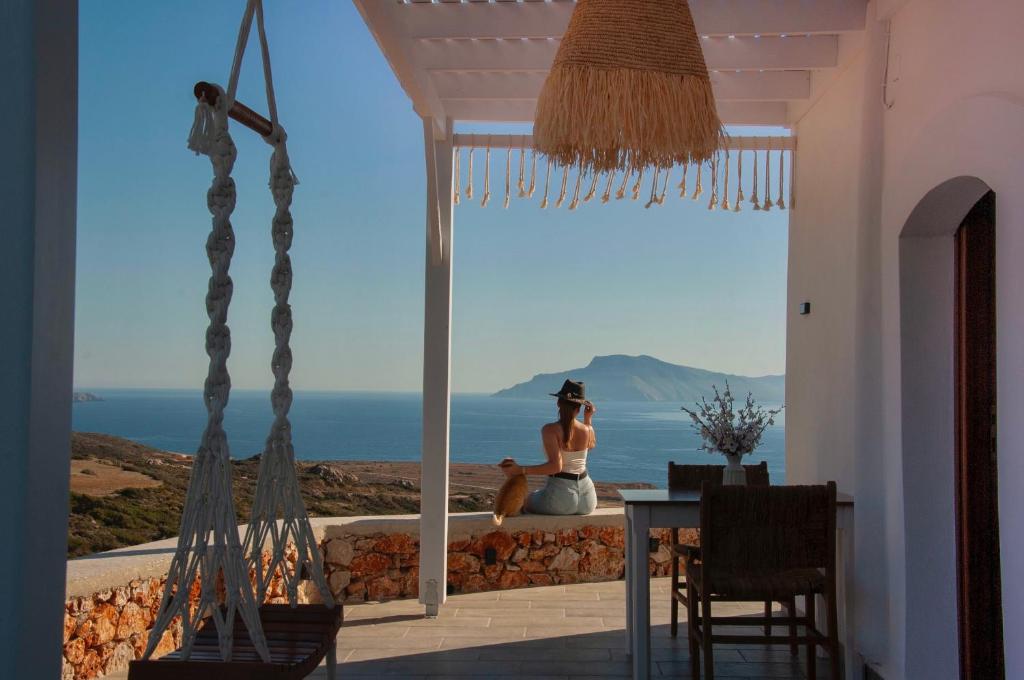 a woman sitting on a balcony looking out at the ocean at Mythos Villa Above the Sunset in Karpathos
