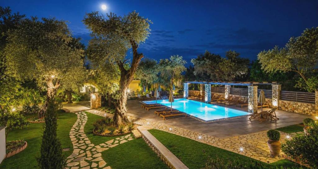 a swimming pool in a garden at night at Vassilis Guest House in Parga