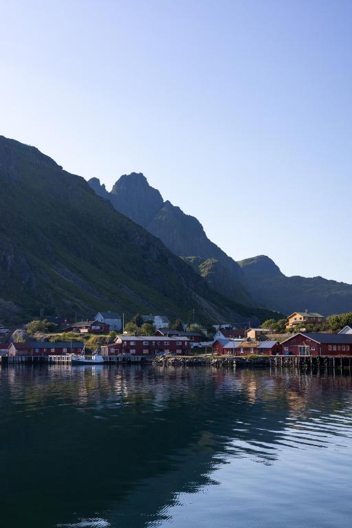 a town on the water with mountains in the background at Gammelbanken Seaview Suites - Modern Apartments with Sea View, Lofoten in Ballstad