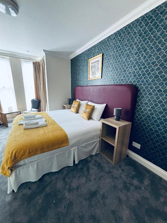 a bedroom with a large bed and a blue wall at Granby Hotel in Gravesend