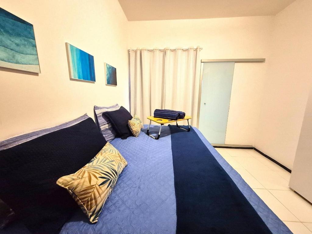 a bedroom with a blue bed with a chair at Apartamento com varanda e VISTA para RUA, TV e 2 suítes in Teixeira de Freitas