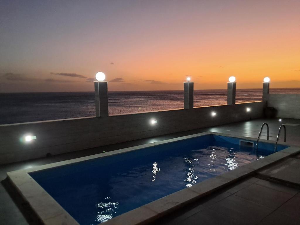 a swimming pool with a view of the ocean at sunset at Riba Mar in Cidade Velha