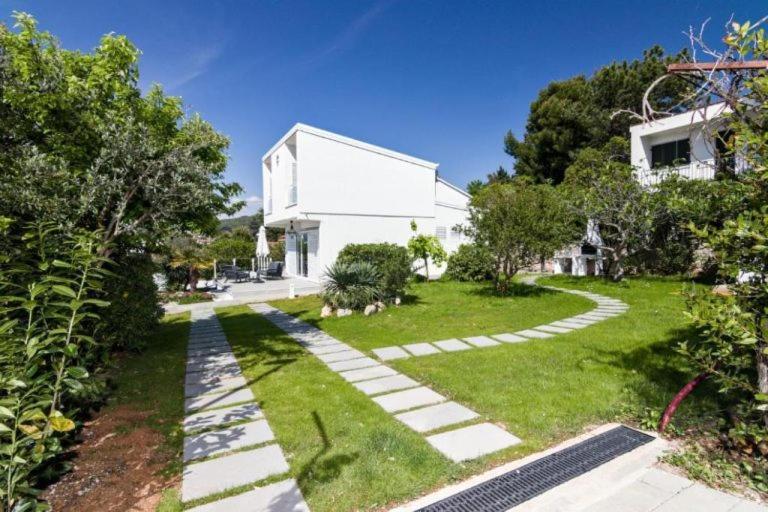 a garden with a white house and a walkway at House Nika in Punat