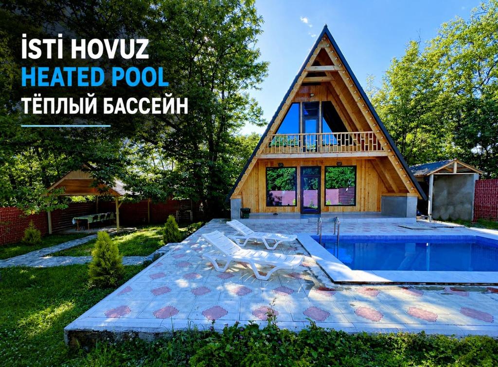 a thatched roof house with a swimming pool at Qafqaz A-Frame Chalet Gabala in Gabala