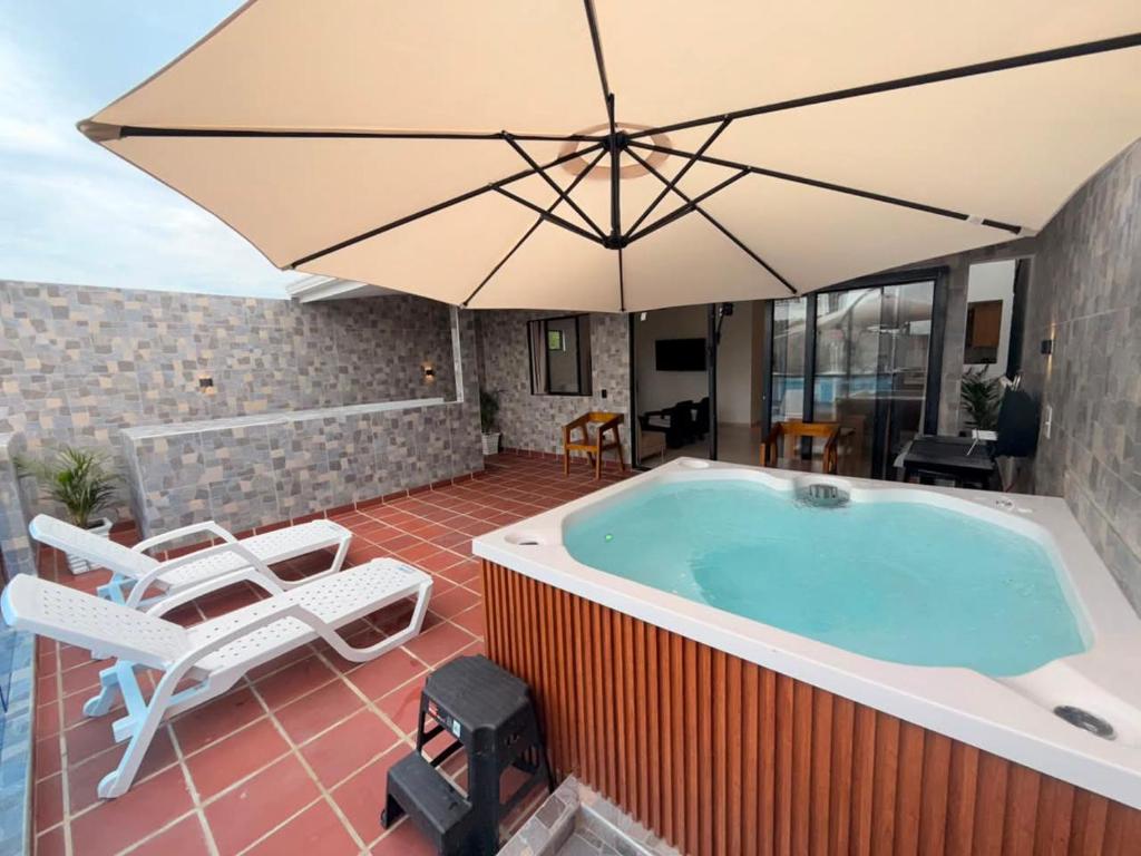 a hot tub with an umbrella on a patio at Cabaña Costa Azul 2 in Coveñitas